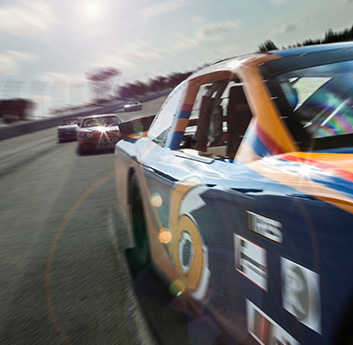A race car with a number on its side, surrounded by motion blur on a track, suggests high speed. Other cars are in the background under a sunny sky.