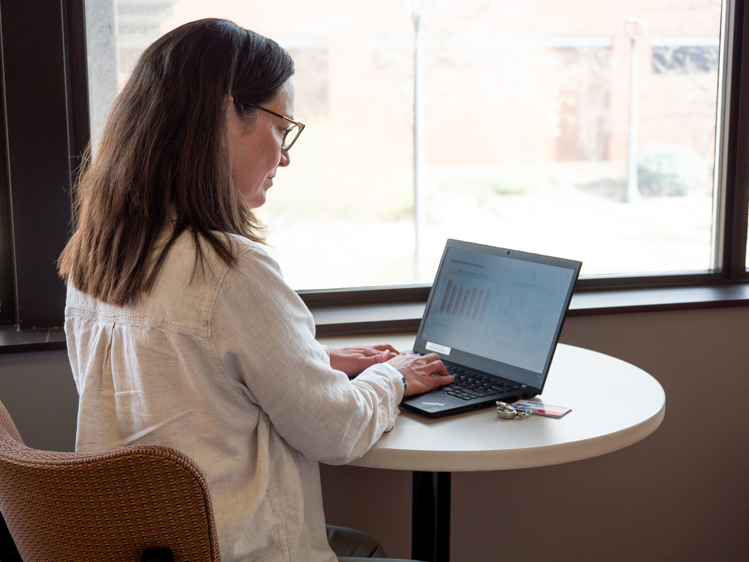 A person is descending a metal staircase at an industrial facility with circular water treatment tanks. It's a sunny day with clear blue skies.