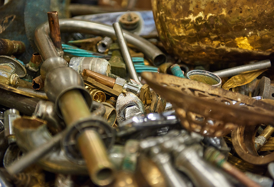 This image shows a pile of various brass musical instrument parts scattered haphazardly, including valves and tubing, with a focus on the disassembled pieces.